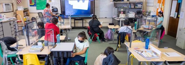 teacher presenting lesson on big screen to students in classroom