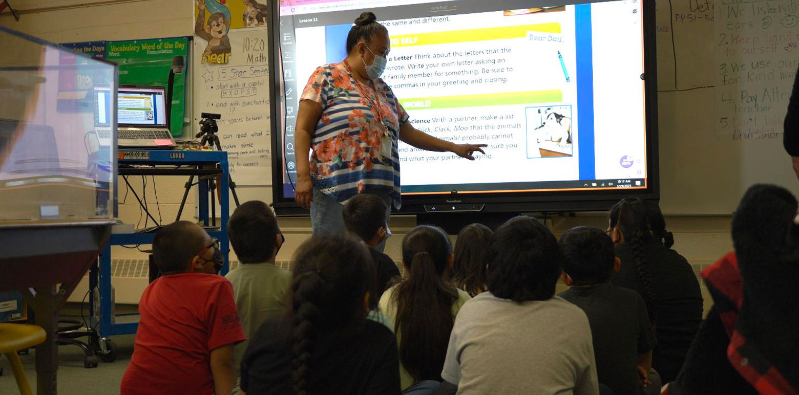 Teacher using digital board to teach a classroom of children.